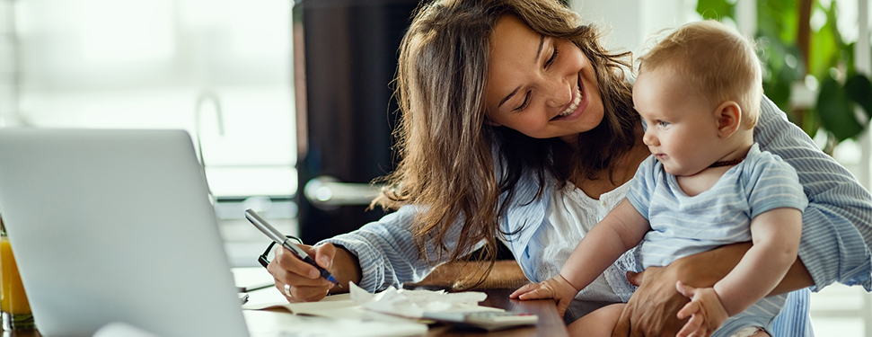 Mother reviewing credit score while holding child.